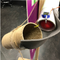 Close up image of ball dispensing mechanism with a red plastic ball loaded in the carboard tubing and stopped by a servo motor